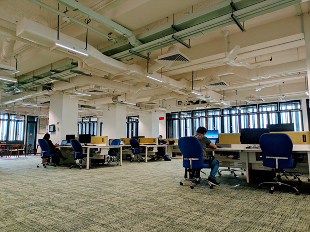 An office space with high ceiling and staff working in their seats.